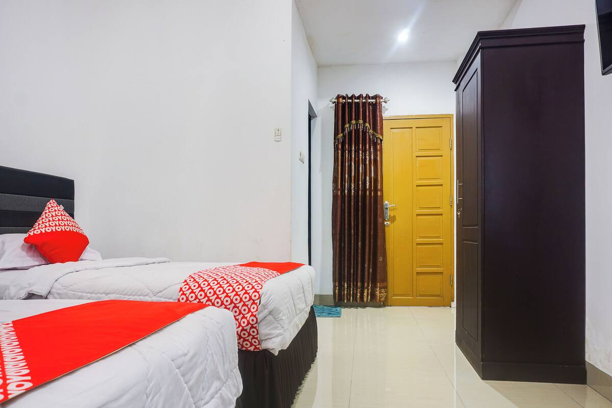 Una habitación de hotel con dos camas, un armario y una puerta.