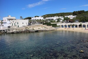 A coastal town with clear waters, white buildings, and a sandy beach.