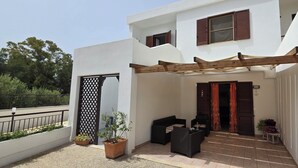 A modern building with a covered patio area, a wooden pergola, and a seating arrangement. - Cottage by the sea of salento (Santa Cateria di Nardo)