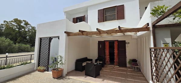 A modern building with a covered patio area, a wooden pergola, and a seating arrangement.