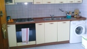 A compact kitchen with a sink, stove, and washing machine. - Cottage by the sea of salento (Santa Cateria di Nardo)