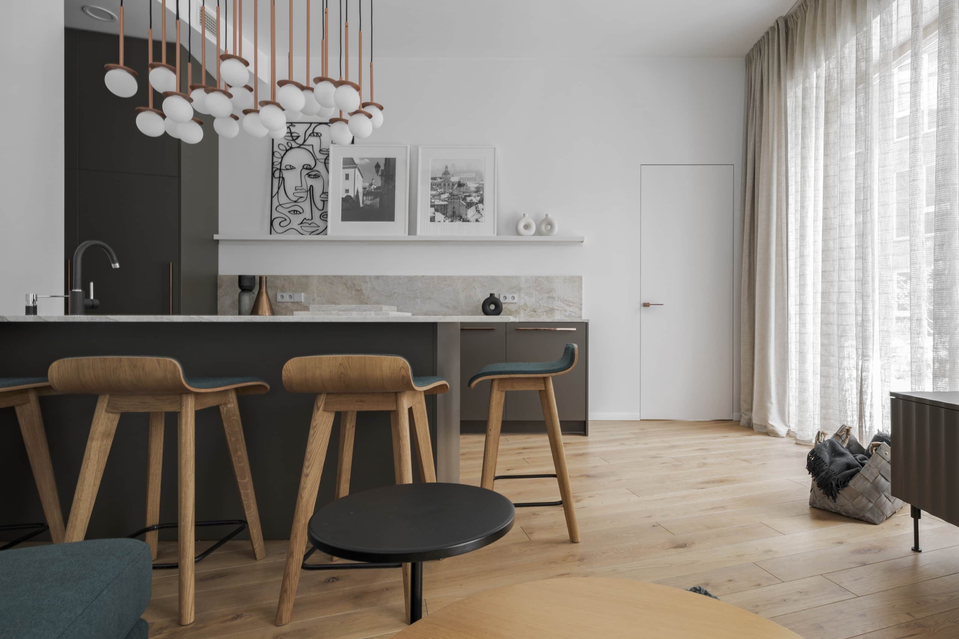 A modern kitchen with wooden bar stools, a marble countertop, and pendant lighting.