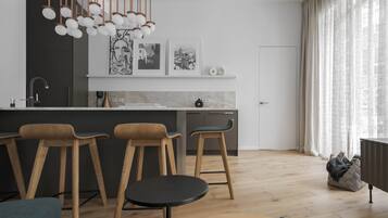 A modern kitchen with wooden bar stools, a marble countertop, and pendant lighting.