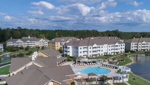 Een resort met meerlaags gebouwen, een zwembad en een meer.