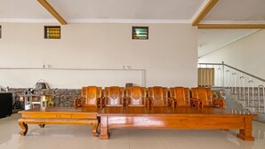 A spacious room with a long wooden table and matching chairs, a stone wall, and a staircase with a metal railing. - SPOT ON 91930 Hotel Citra Dewi 4 Manunggal (Bandungan)