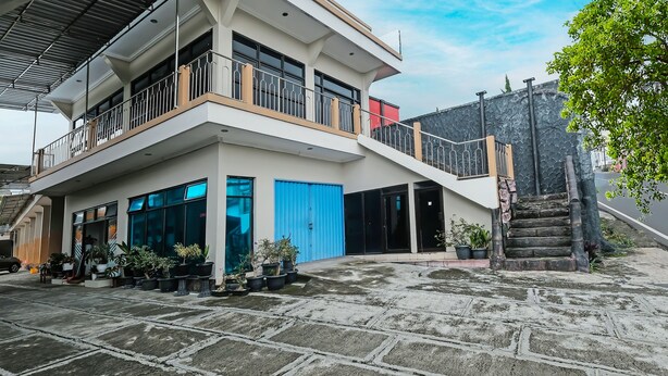 A modern building with a two-story balcony, large windows, and a blue garage door. - SPOT ON 91930 Hotel Citra Dewi 4 Manunggal (Bandungan)