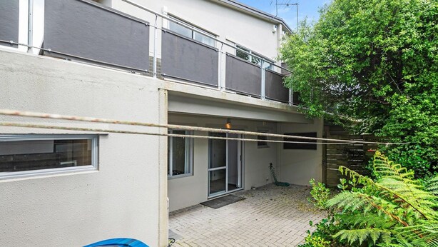 A two-story building with a balcony, a covered outdoor area, and a garden with ferns. - Adventure Trails - Spa Pool, Walk to Redwoods (Rotorua)