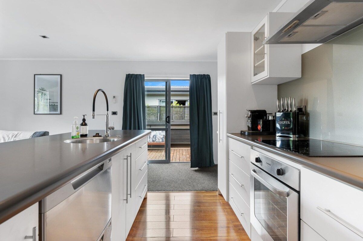 A modern kitchen with stainless steel appliances, a built-in oven, and a view to the outside.