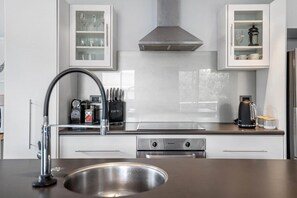Una cucina moderna con elettrodomestici in acciaio inossidabile, forno a incasso e cappa aspirante.