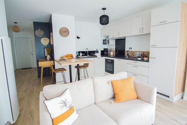 A modern kitchen with white cabinets, a black countertop, and a dining area with a wooden table and bar stools.