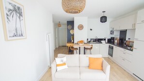 A modern living room with a sofa, a coffee table, and a dining area with a table and chairs. - -SHELBY- T2 ARRIÈRE CORNICHE PARKING ET TERRASSE (Concarneau)