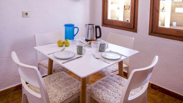 Un comedor con una mesa blanca, sillas y un ventanal con vistas a edificios.