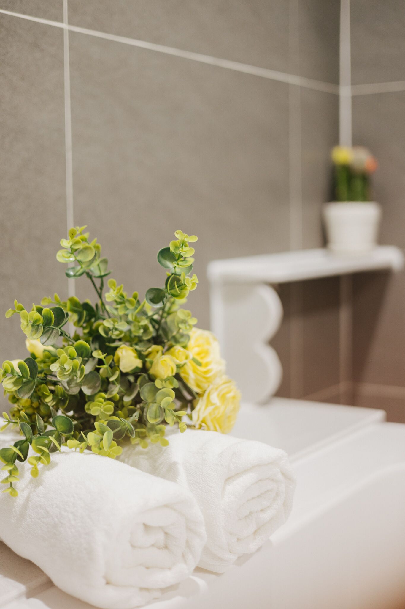 Un baño ordenado con una toalla blanca y una planta pequeña sobre una superficie blanca.