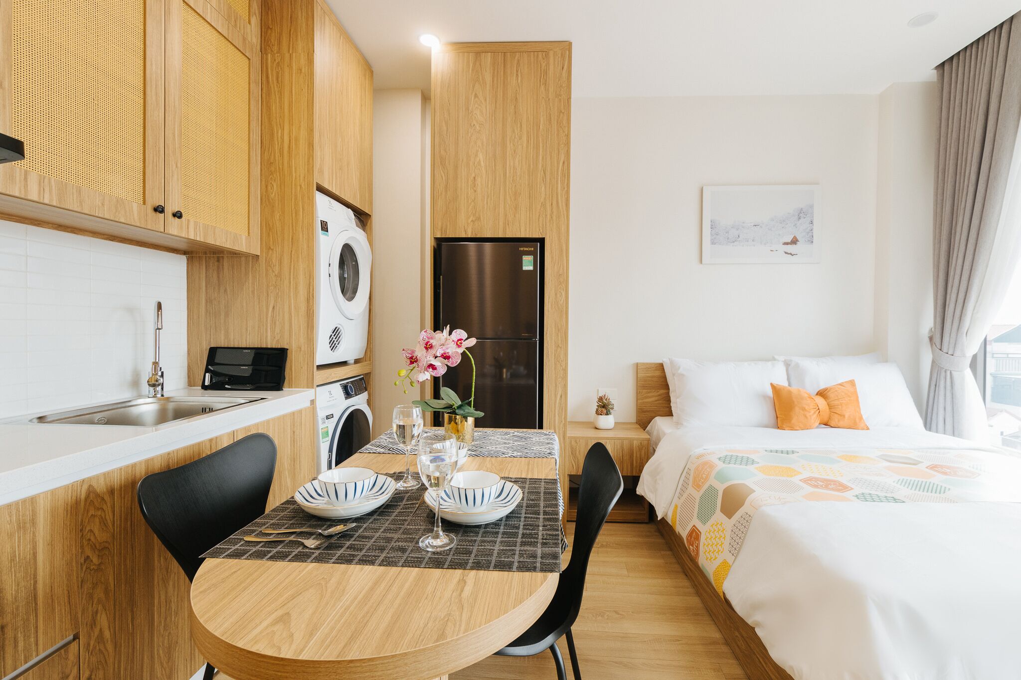 A compact hotel room with a kitchenette, a dining area, and a bed.