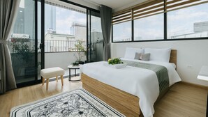 A modern bedroom with a large bed, a small stool, a side table, and a view of the city through large windows. - Myrcella Urban Studio (Hanoi)