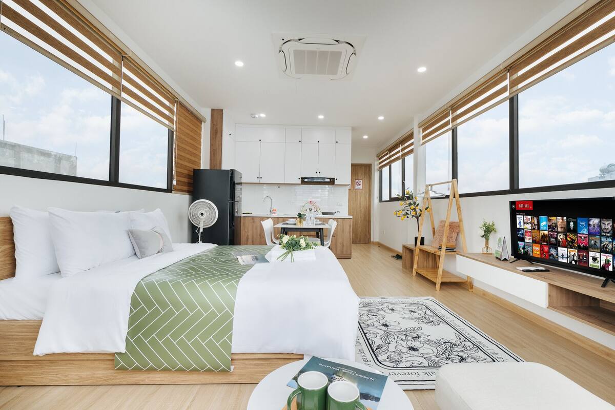 Quarto de hotel moderno com cama, área de refeições, TV e vista para a cidade.