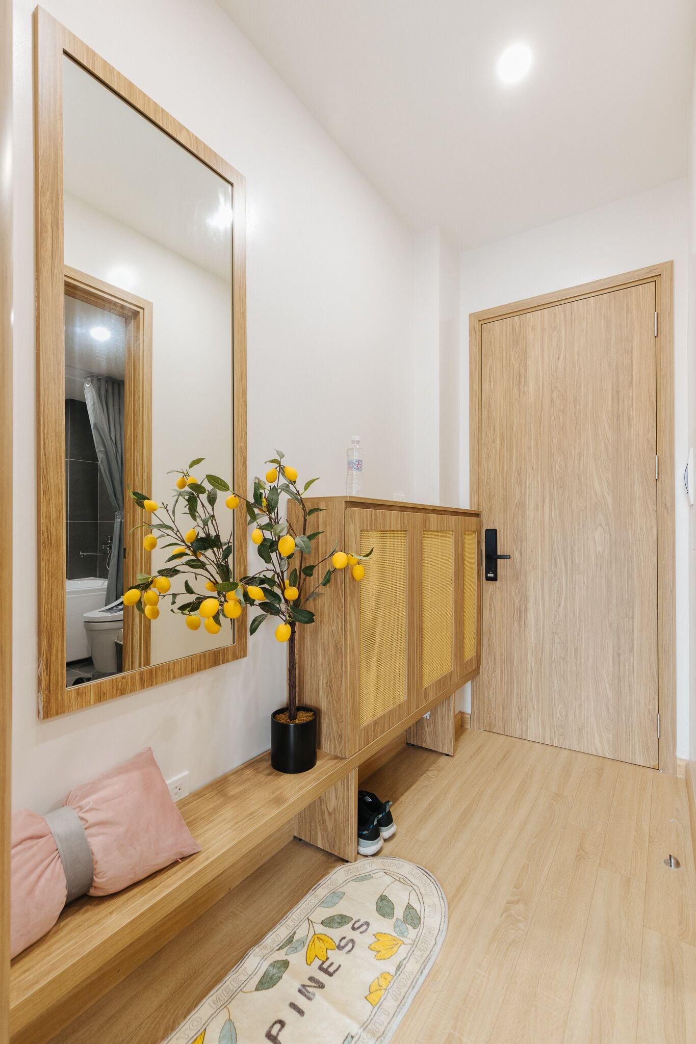 A bathroom with a wooden vanity, a mirror, a potted plant, and a shower area.