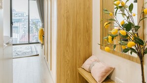 A modern hotel room with a wooden accent wall, a large mirror, a potted plant, and a bench with a cushion. - Myrcella Urban Studio (Hanoi)