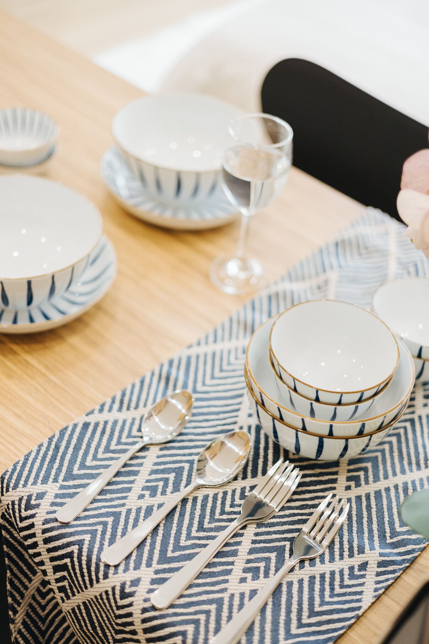 A dining table set with white plates, blue and white patterned bowls, and silver cutlery.