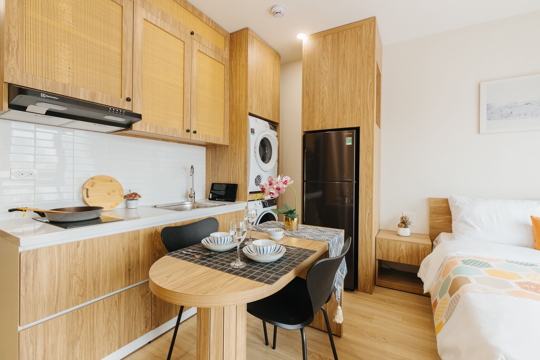 Cocina compacta con armarios de madera, lavadora integrada y un refrigerador moderno.