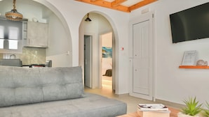 Una sala de estar moderna con un sofá gris, una mesa de madera y un televisor montado en la pared.