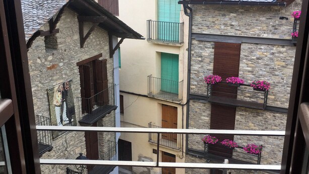 Blick vom Balkon auf eine traditionelle europäische Stadt mit Steinhäusern, Holzbalkonen und Blumenkästen.