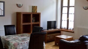 Ein Essbereich mit Tisch, Stühlen, einem Fernseher und einem Bücherregal.