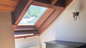 Ein Schlafzimmer mit schrägem Dach, einem Oberlicht, einem Schminktisch und einer Heizung.