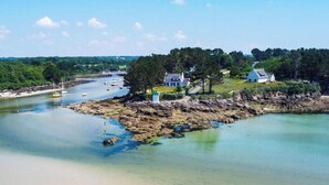 Een kustlandschap met een zandstrand, een rotsachtige kustlijn en enkele huizen nabij het water.