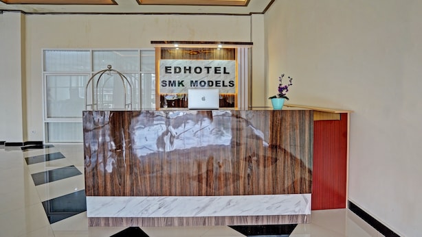 A reception desk with a marble top and a sign reading "EDHOTEL SMK MODELS". - OYO 91997 Edhotel Smk Models Syariah (Kesilir)
