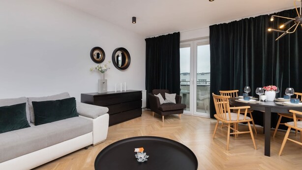 A modern living room with a sofa, a coffee table, a dining table set for four, and a chair.