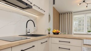 Una cocina moderna con protector contra salpicaduras de mármol, grifo negro y encimera de madera.