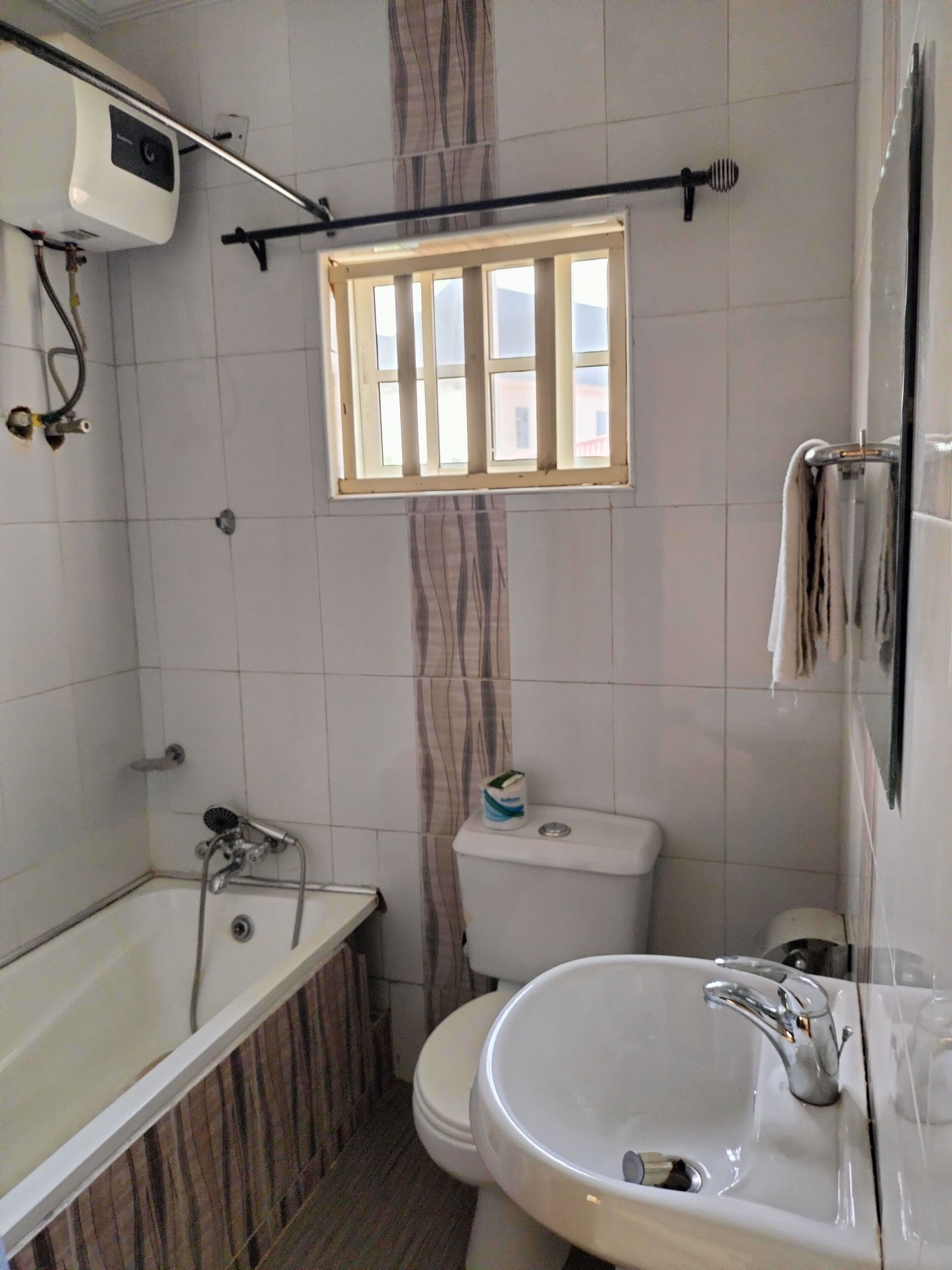 Un baño con bañera, inodoro, lavabo y ventana.