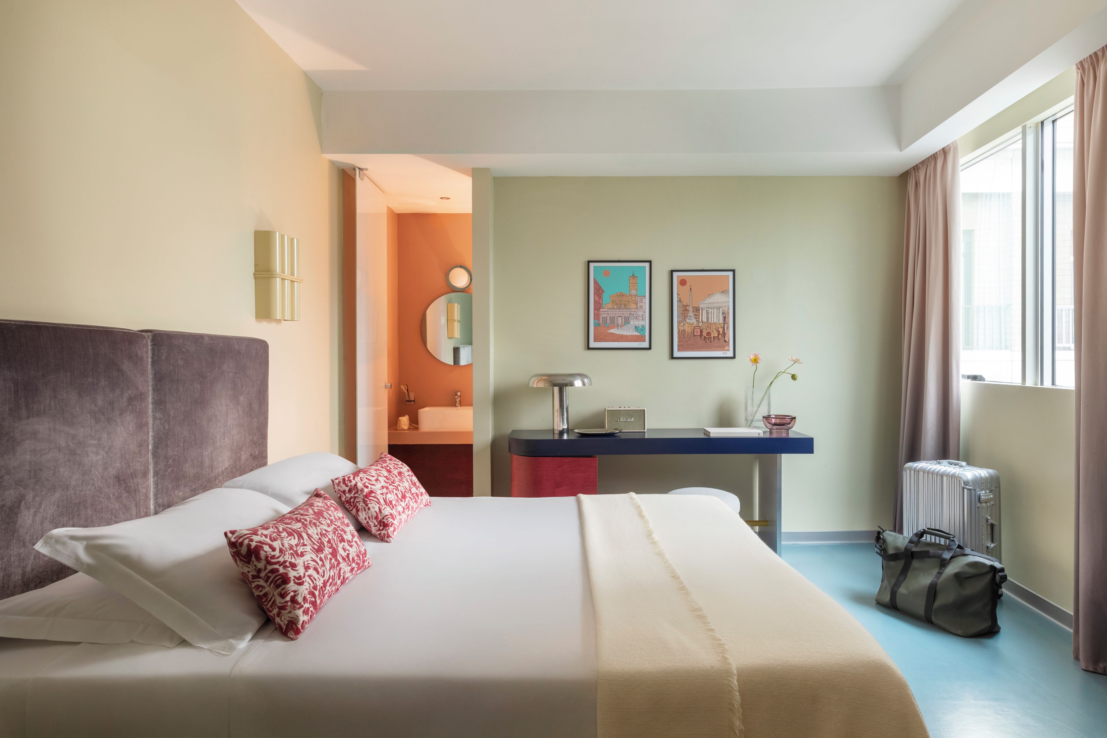 A hotel room with a bed, desk, and window.