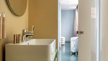 A bathroom with a large mirror, a sink, and toiletries on a green cabinet.