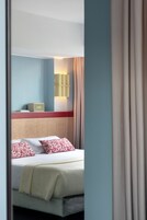 A hotel room with a bed, a bedside table, a lamp, and a window with curtains.