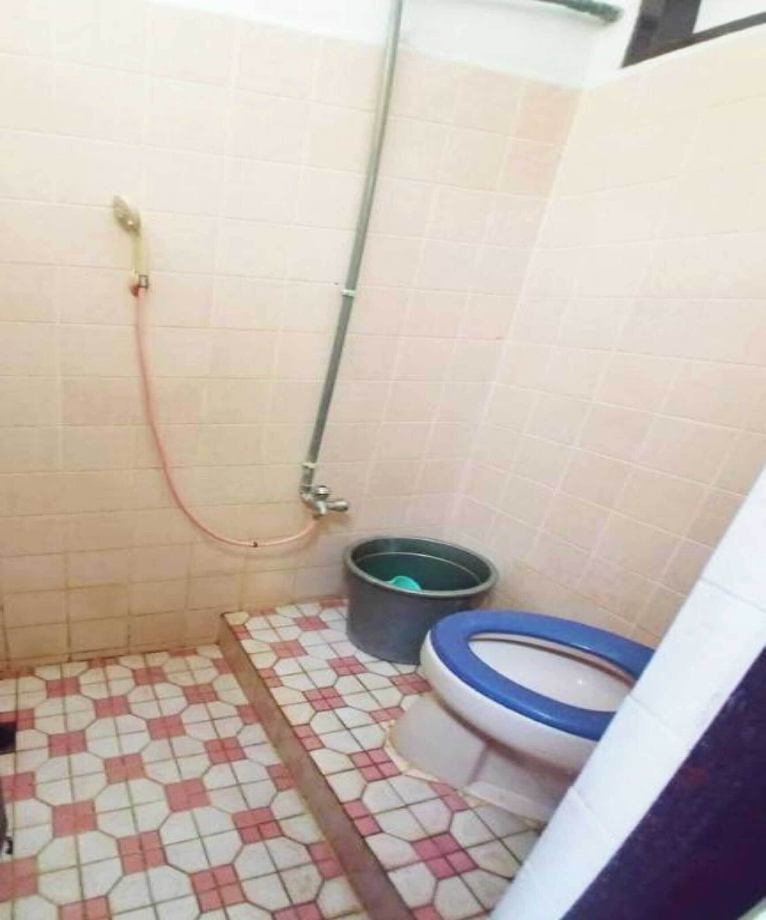 A small bathroom with a toilet, a shower, and a tiled floor.