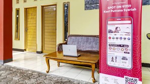 Un hall d’hôtel avec une table en bois, un canapé et une affiche publicitaire rouge.
