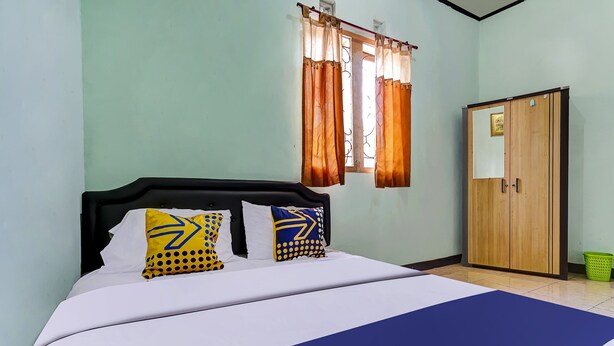 Une chambre à coucher avec un lit, des rideaux, une armoire et une fenêtre.