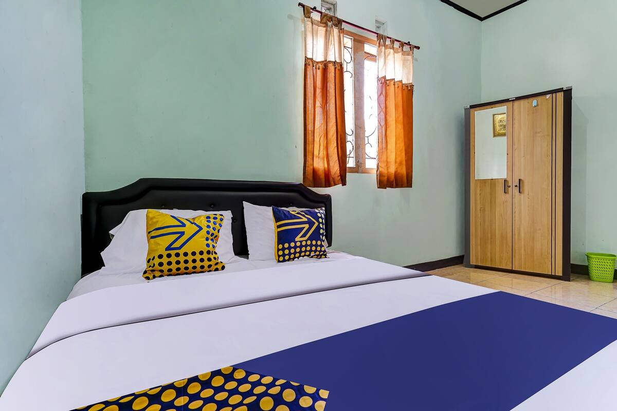 Un dormitorio con cama, cortinas, armario y ventana.