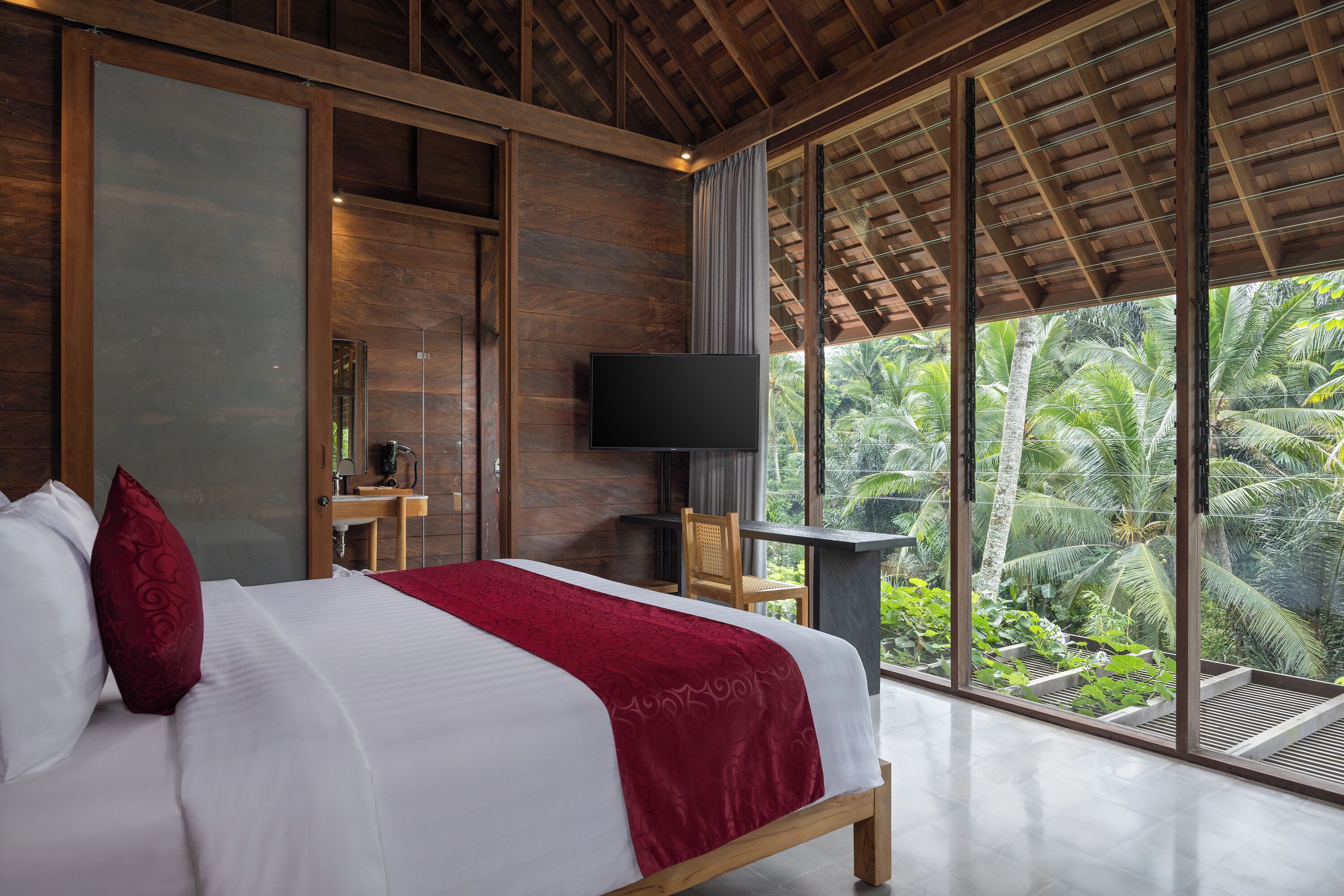 Une chambre avec un grand lit, une télévision et une vue sur la végétation tropicale.