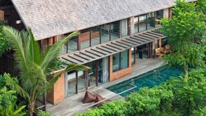 Una casa moderna con un amplio ventanal, piscina y terraza de madera.