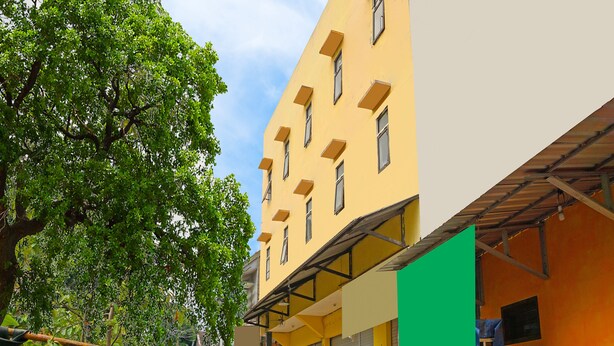 A yellow building with multiple windows and a green awning. - OYO 91401 Almeera (Malang)