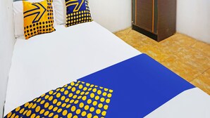 A bed with a white and blue bedspread, two pillows with yellow and blue patterns, and a blue headboard. - OYO 91401 Almeera (Malang)