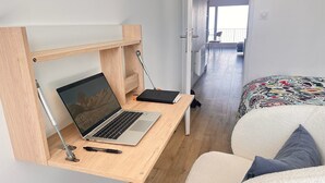 Una habitación pequeña con un escritorio de madera, una computadora portátil, un bolígrafo y una silla.