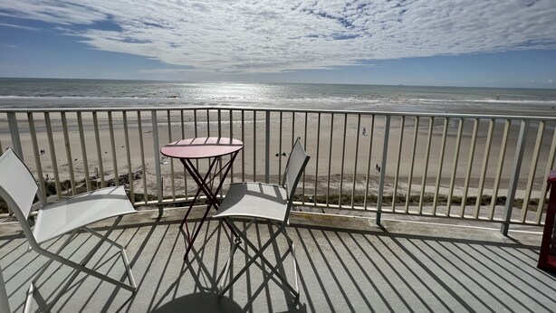 Un balcón con mesa y sillas con vista a la playa.
