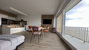 Una habitación de hotel moderna con un balcón amplio, un comedor y una cocina.