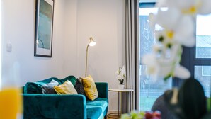 Moderni olohuone, jossa on turkoosinsininen sohva, pieni pyöreä pöytä ja lattiavalaisin.