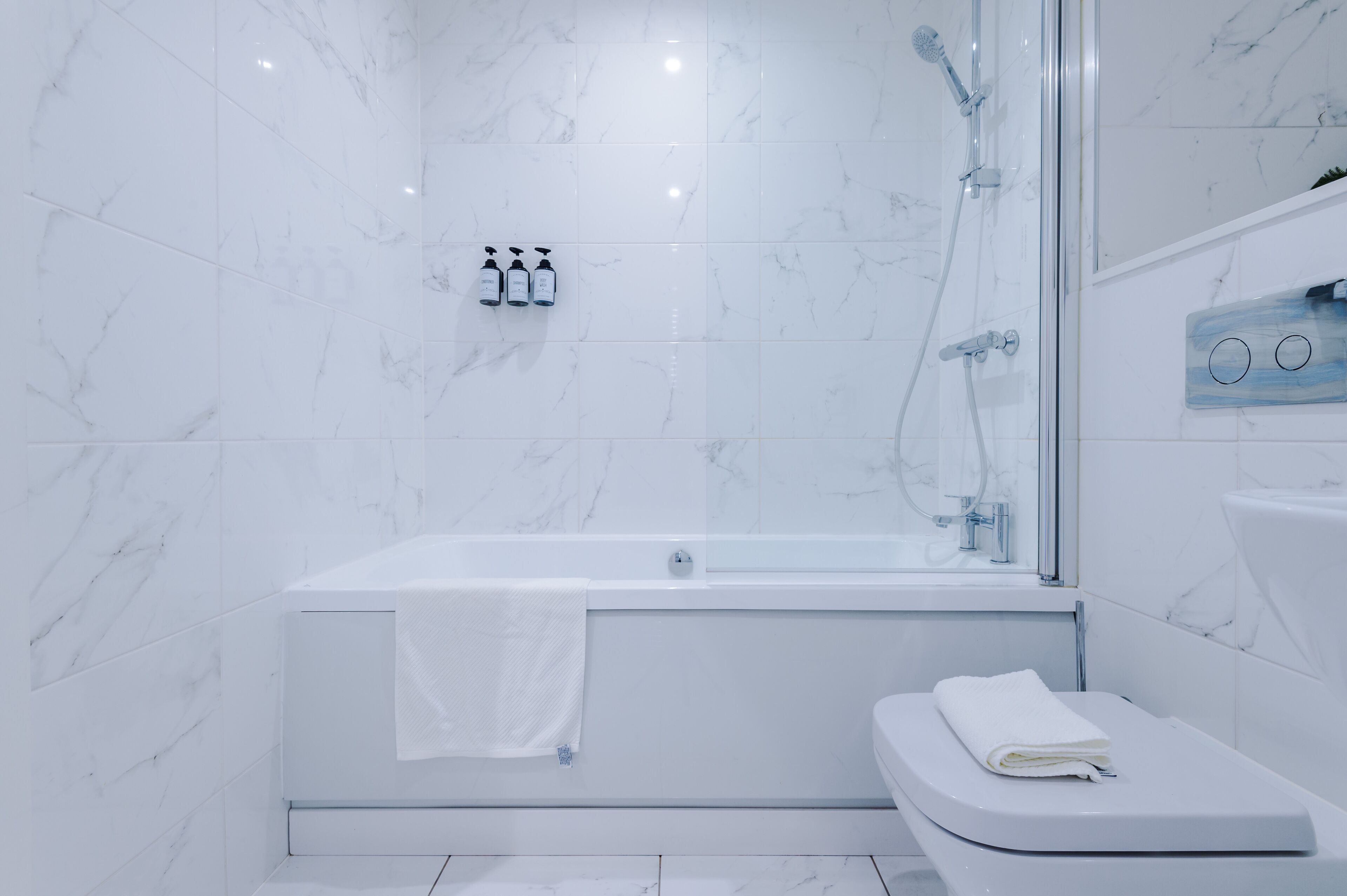 A modern bathroom with a bathtub, shower, and toilet.