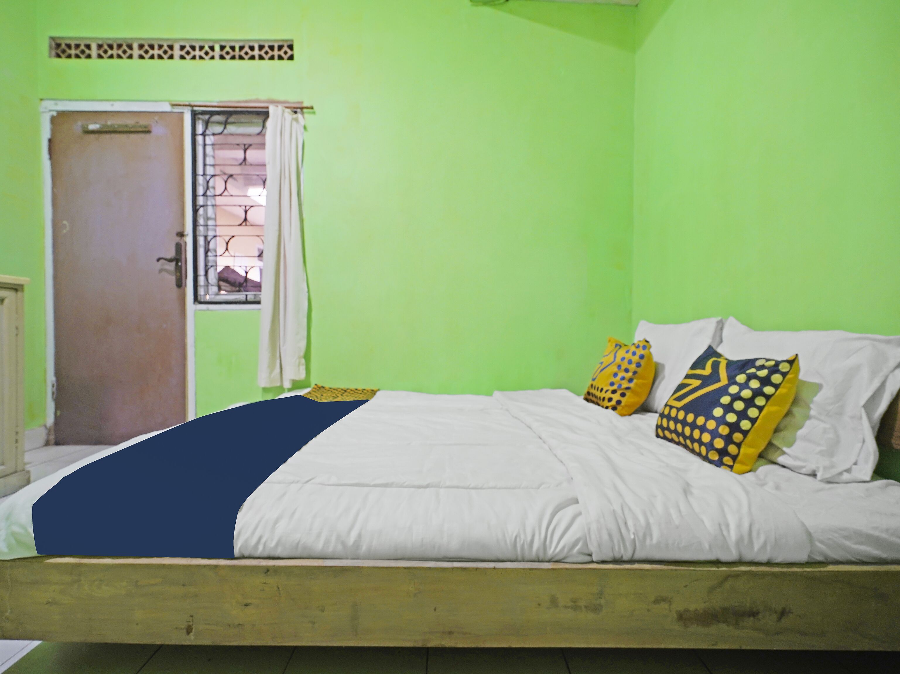 A room with a bed, a window with curtains, and a door.
